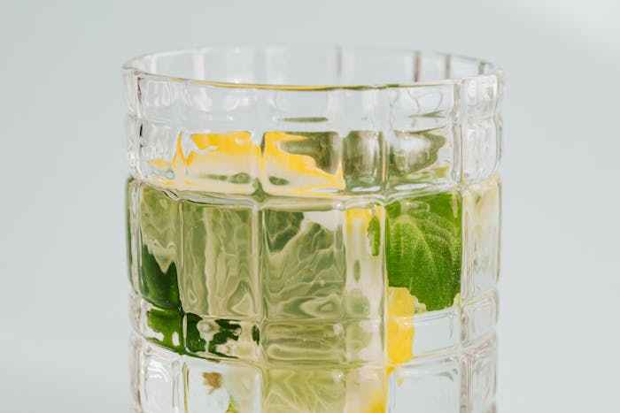 A close-up of a refreshing glass of lemon ginger turmeric tea with sliced lemons and mint leaves, highlighting the numerous lemon ginger turmeric tea benefits for health and wellness.